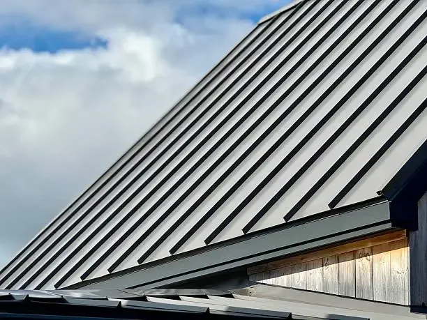 Standing seam metal roof slope above a wood soffit